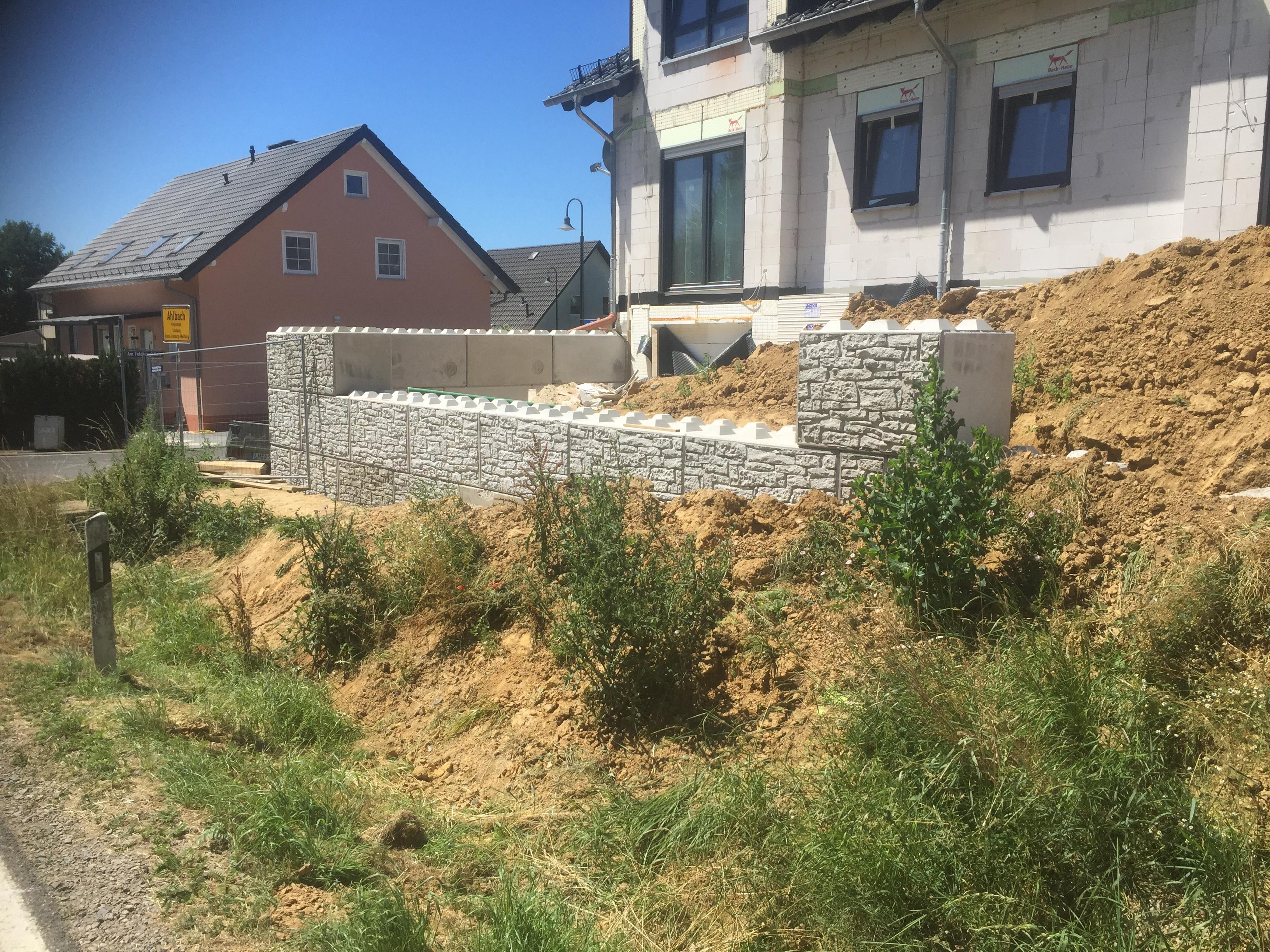 Mauer aus Betonsteinen im Garten vor einem Haus